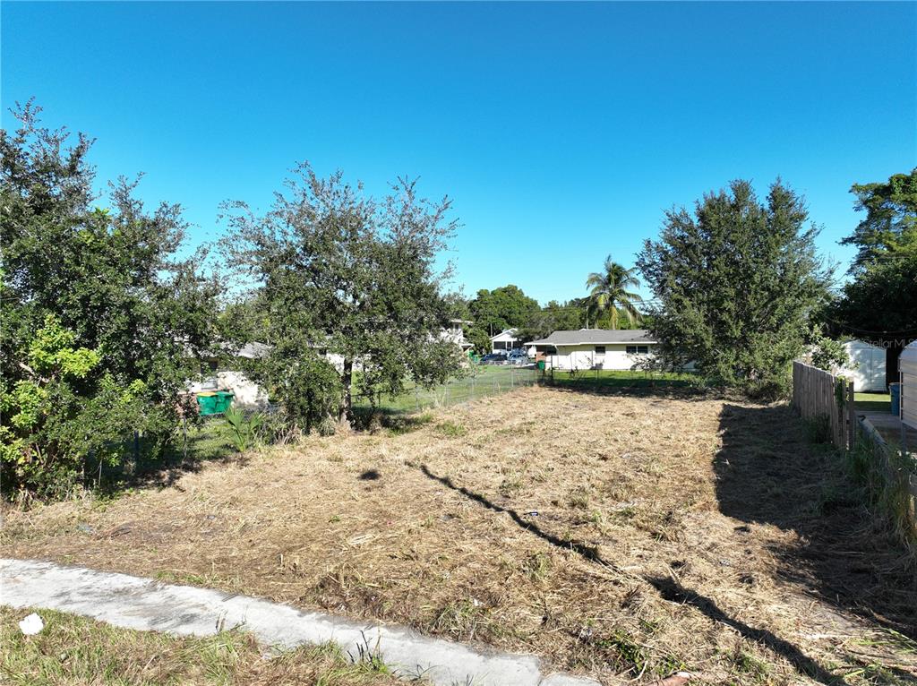 A vacant, cleared residential lot with grass and trees under a clear blue sky — 478 ROOSEVELT AVENUE, MERRITT ISLAND, FL