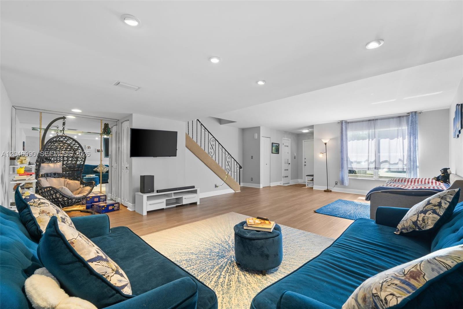 A living room features blue sofas, a hanging chair, a television, and a staircase — 801 NE 27th Ave, Hallandale Beach FL 33009, HALLANDALE BEACH, FL