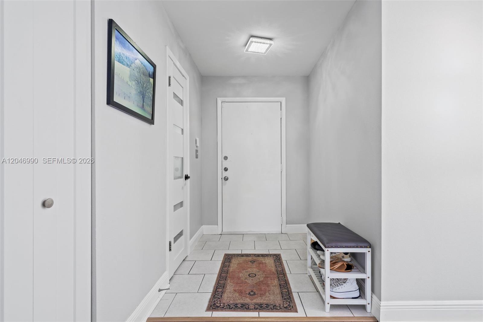 A bright entryway features white walls, tiled flooring, a shoe bench, and a front door — 801 NE 27th Ave, Hallandale Beach FL 33009, HALLANDALE BEACH, FL