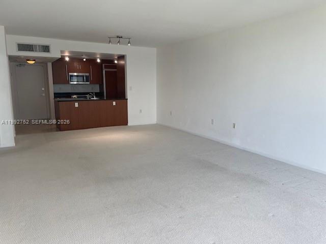 An open-plan living area features beige carpeting and an adjacent kitchen with dark wood cabinets — 10275 Collins Ave # 1107, Bal Harbour FL 33154, BAL HARBOUR, FL