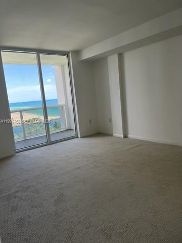 An empty room with beige carpeting and a sliding glass door overlooking the ocean — 10275 Collins Ave # 1107, Bal Harbour FL 33154, BAL HARBOUR, FL