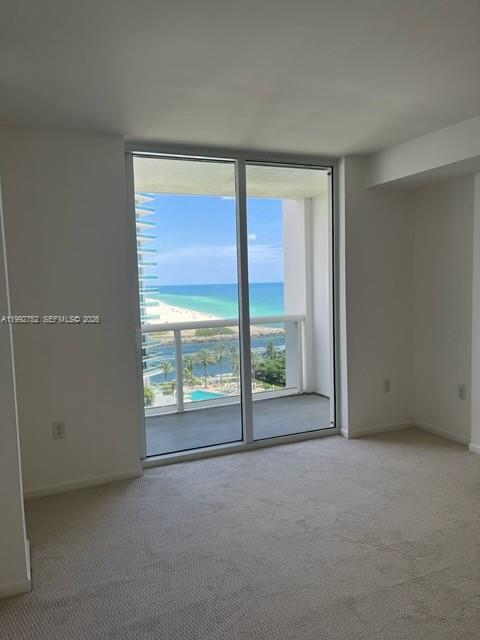 An empty carpeted room features a large sliding glass door overlooking the ocean and beach — 10275 Collins Ave # 1107, Bal Harbour FL 33154, BAL HARBOUR, FL