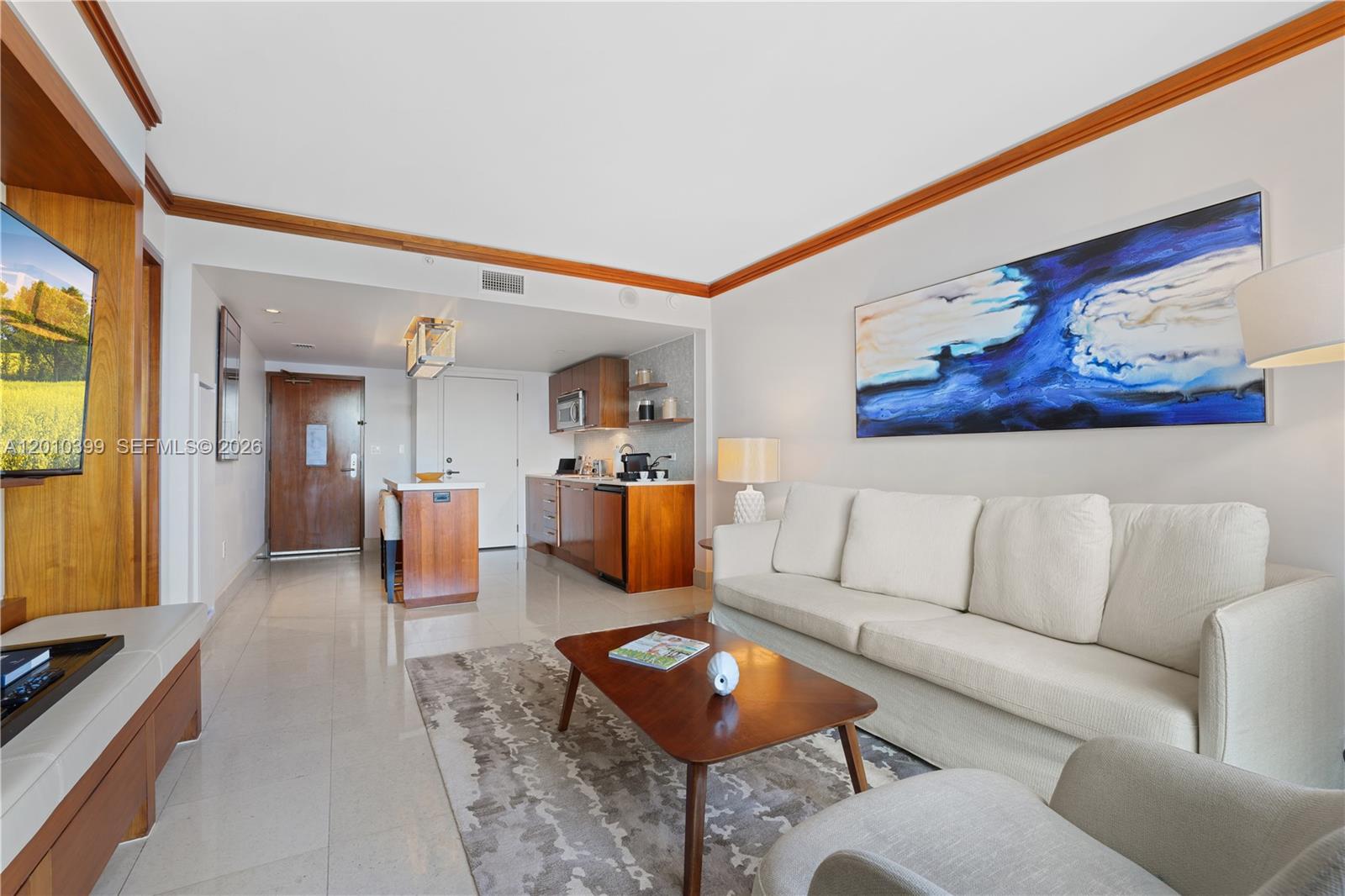 A living room features a white sofa, a wooden coffee table, and an open kitchenette — 6801 Collins Ave # 503, Miami Beach FL 33141, MIAMI BEACH, FL