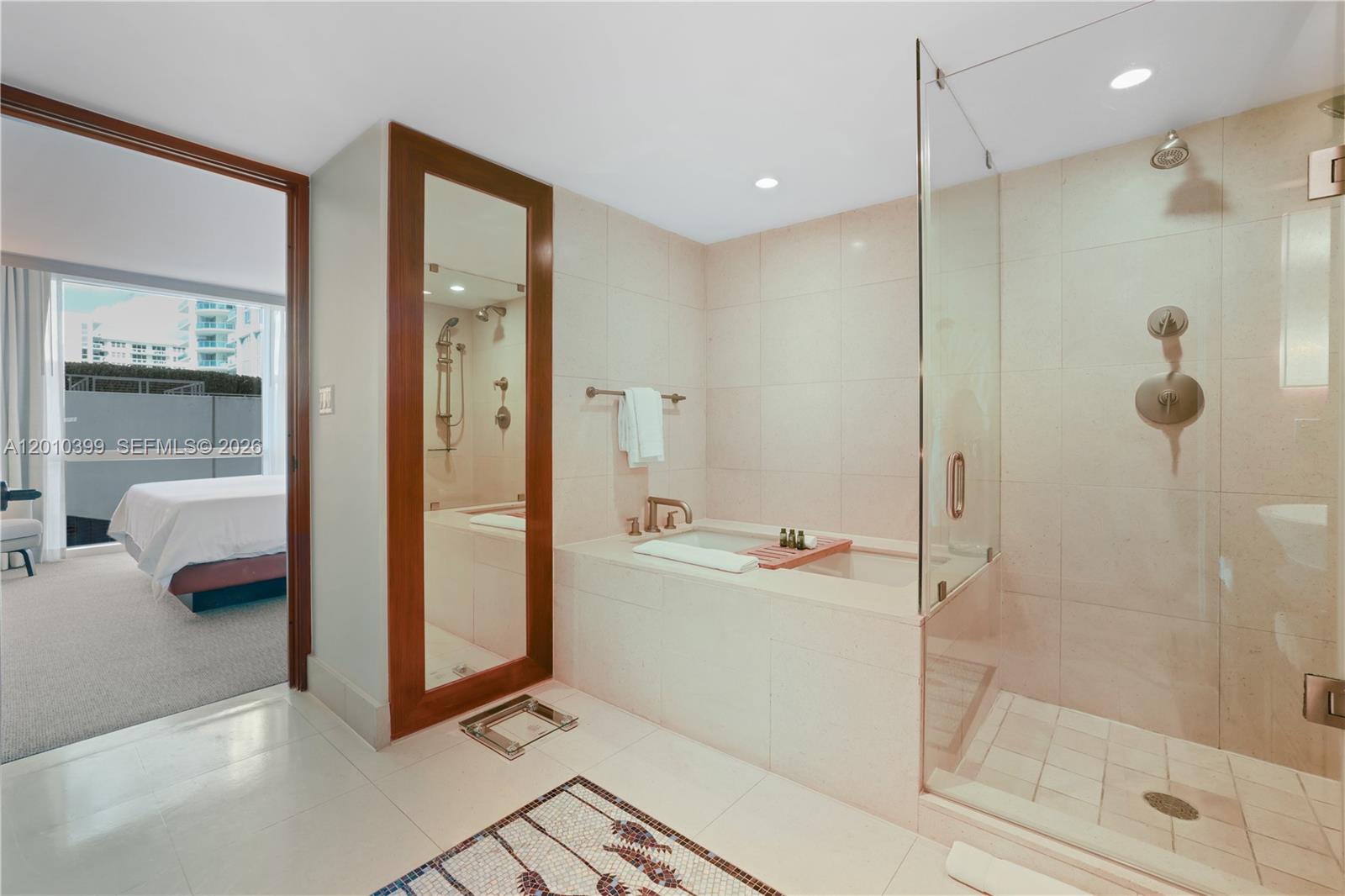 A bathroom features a glass-enclosed shower, a built-in bathtub, and a full-length mirror — 6801 Collins Ave # 503, Miami Beach FL 33141, MIAMI BEACH, FL