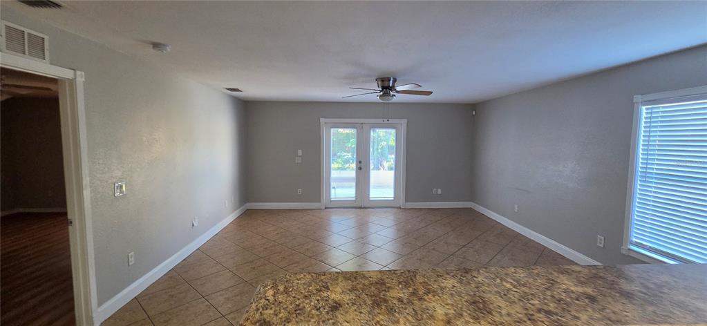 A living room with tile flooring, a ceiling fan, and French doors leading outside — 6807 E NORTH BAY STREET, TAMPA, FL