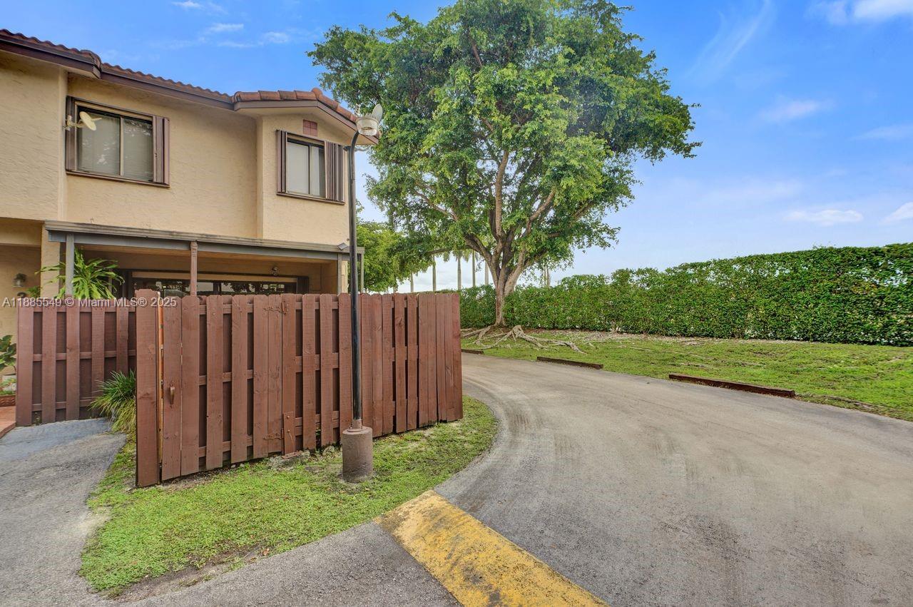 A tan two-story townhouse exterior with a wooden privacy fence and a paved driveway — 14201 SW 57th Ln, Miami FL 33183, MIAMI, FL