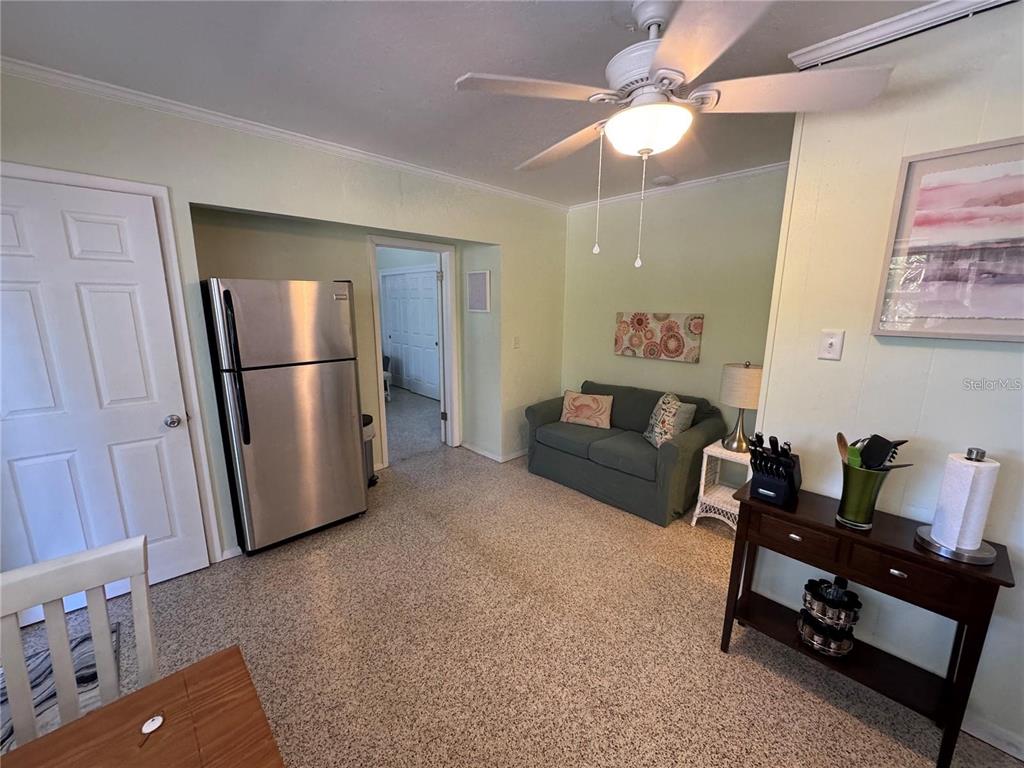 A room with a stainless steel refrigerator, a green loveseat, and a ceiling fan — 104 BASE AVENUE W UNIT C, VENICE, FL