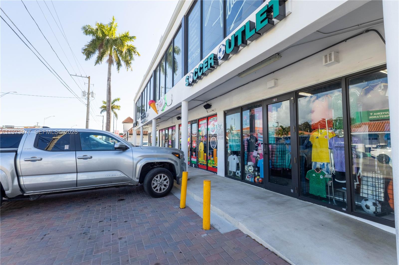 A silver pickup truck is parked in front of a storefront labeled Soccer Outlet — 700 SW 17th Ave, Miami FL 33135, MIAMI, FL