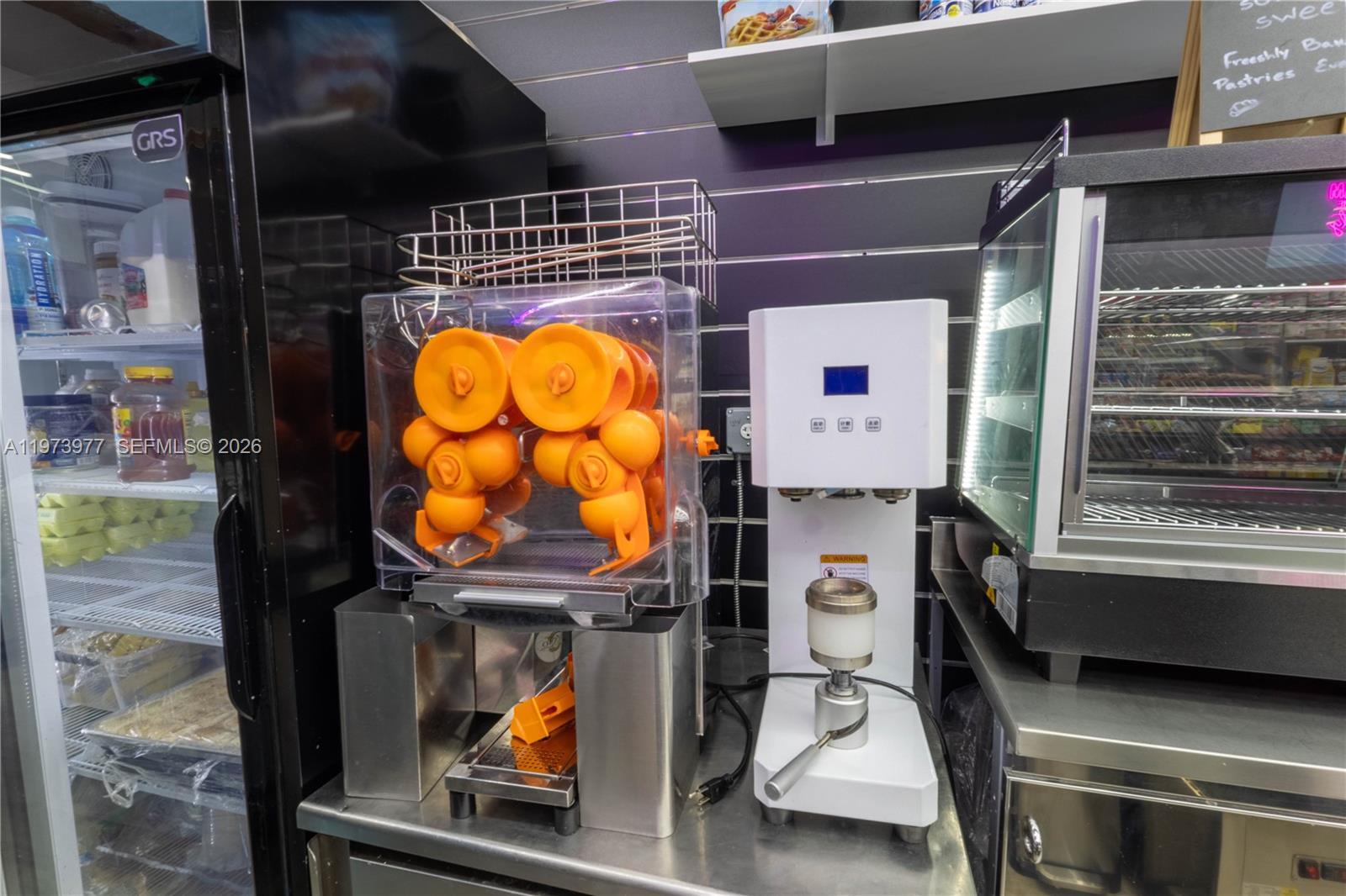 A commercial kitchen counter features an orange juice machine and a cup sealing machine — 700 SW 17th Ave, Miami FL 33135, MIAMI, FL