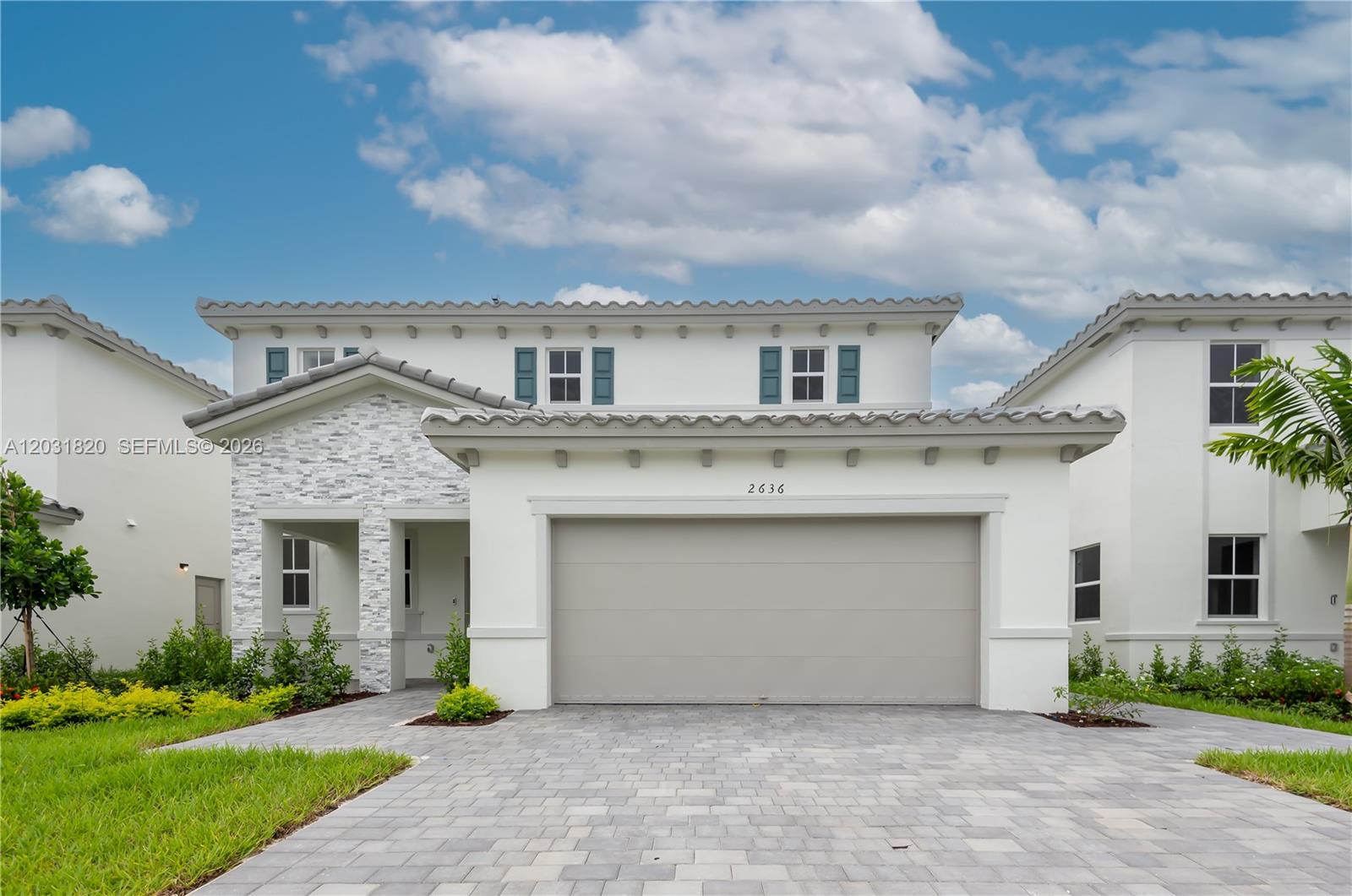 A two-story house features a stone-accented entryway, a two-car garage, and teal window shutters — 2636 SE 8th Ct, Homestead FL 33035, HOMESTEAD, FL