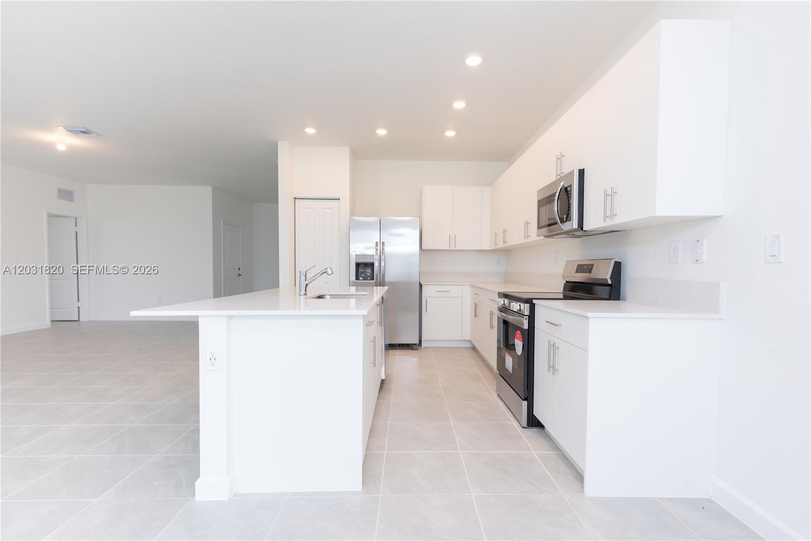 A modern kitchen features white cabinets, stainless steel appliances, and a large central island — 2636 SE 8th Ct, Homestead FL 33035, HOMESTEAD, FL