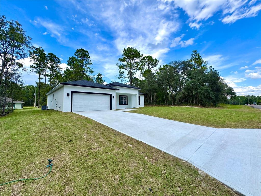 A white, single-story house with a black roof and a concrete driveway — 2077 W LINDEN DRIVE, CITRUS SPRINGS, FL