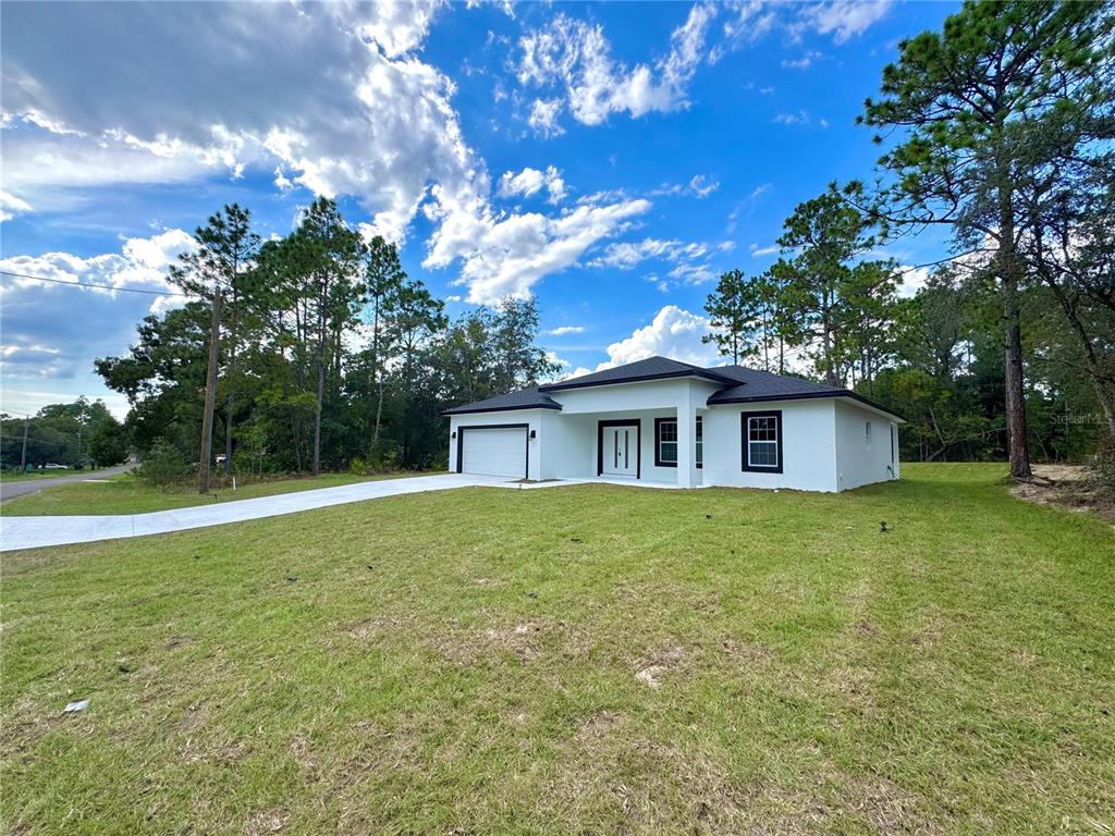 A newly constructed white house with a black roof and garage sits on a lawn — 2077 W LINDEN DRIVE, CITRUS SPRINGS, FL
