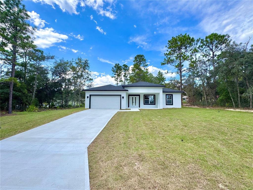 A modern, white single-story house with a black roof and garage sits on a grassy lot — 2077 W LINDEN DRIVE, CITRUS SPRINGS, FL