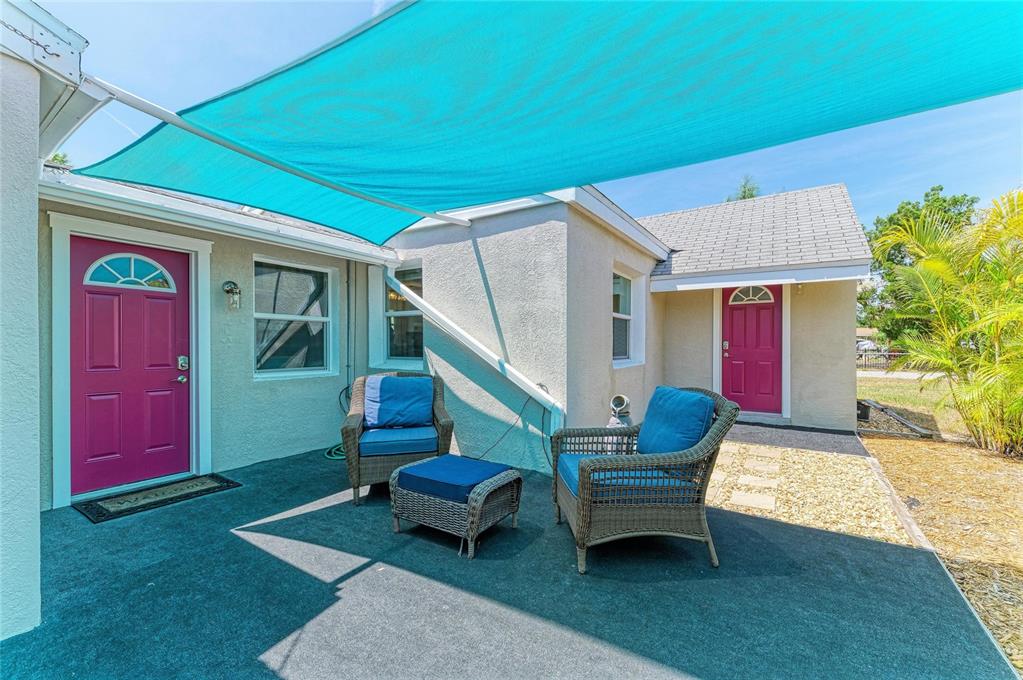 A patio with two wicker chairs, an ottoman, and a turquoise shade sail overhead — 901 OAK STREET SW, RUSKIN, FL