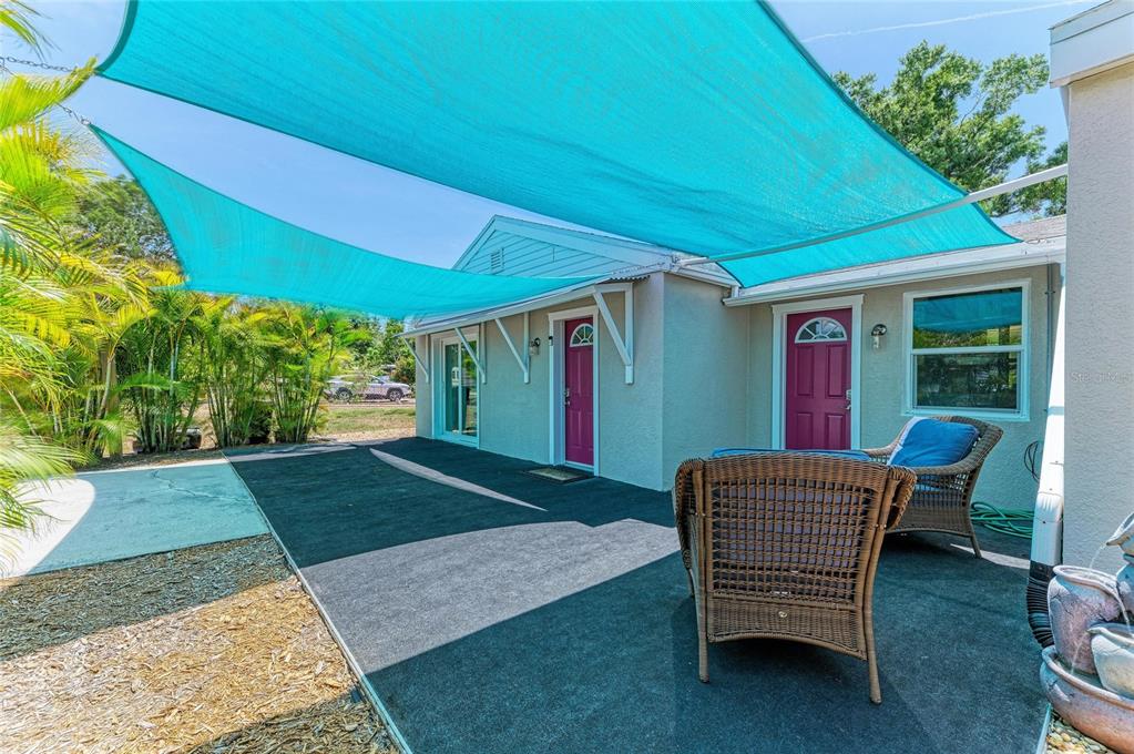 A patio area with a blue shade sail, wicker furniture, and two exterior doors — 901 OAK STREET SW, RUSKIN, FL
