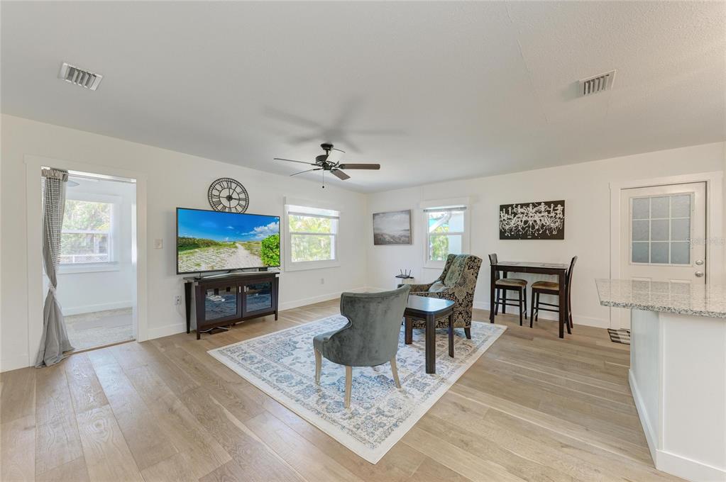 A living room features light wood flooring, a television, two armchairs, and a dining set — 901 OAK STREET SW, RUSKIN, FL