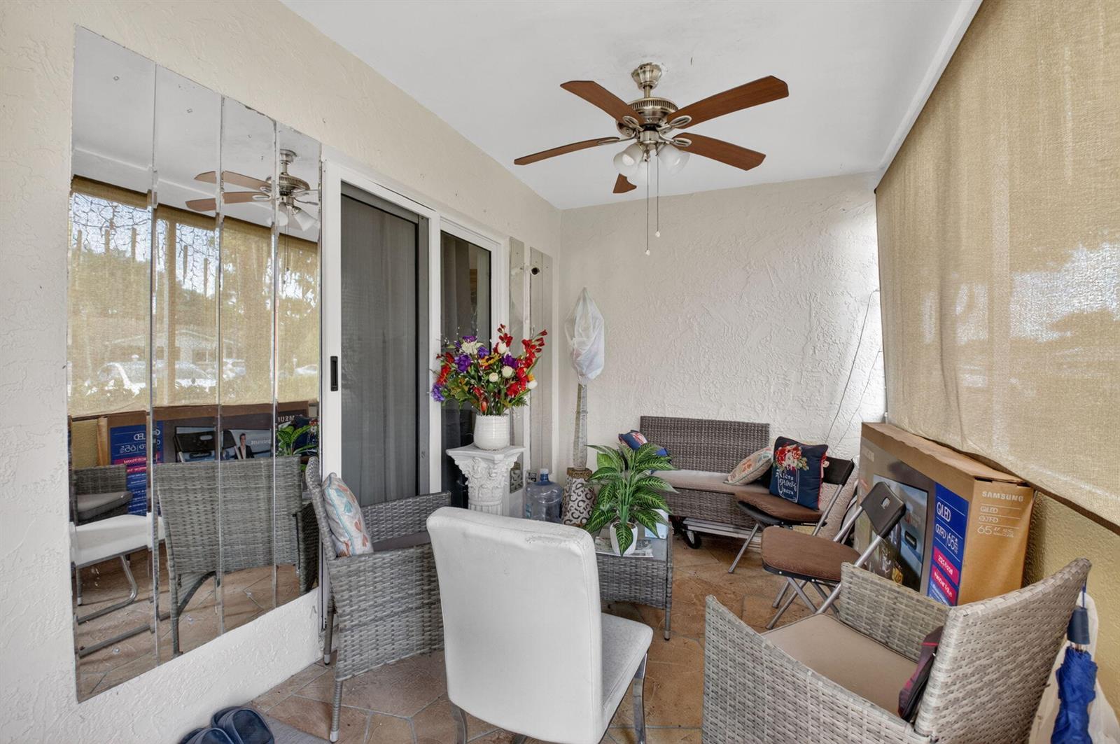 A covered patio features wicker furniture, a ceiling fan, tiled flooring, and a mirrored wall — 14232 Campanelli Drive, Delray Beach FL 33484, DELRAY BEACH, FL