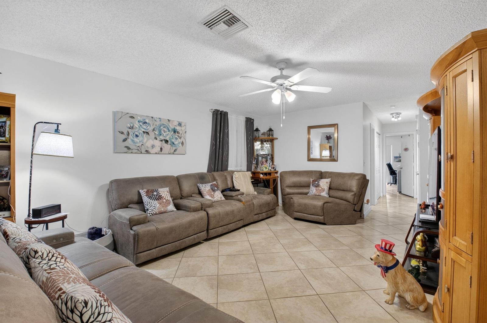 A living room features tile flooring, a ceiling fan, and multiple brown reclining sofas — 14232 Campanelli Drive, Delray Beach FL 33484, DELRAY BEACH, FL
