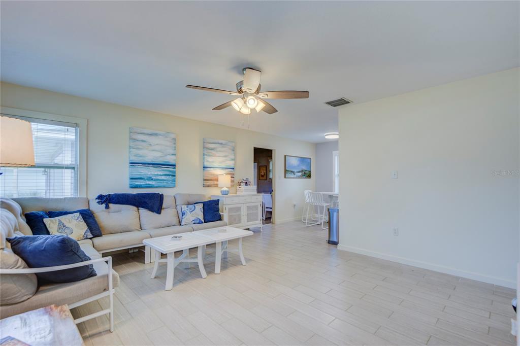 A living room features light tile floors, a ceiling fan, and a sectional sofa — 3200 W DE BAZAN AVENUE, ST PETE BEACH, FL