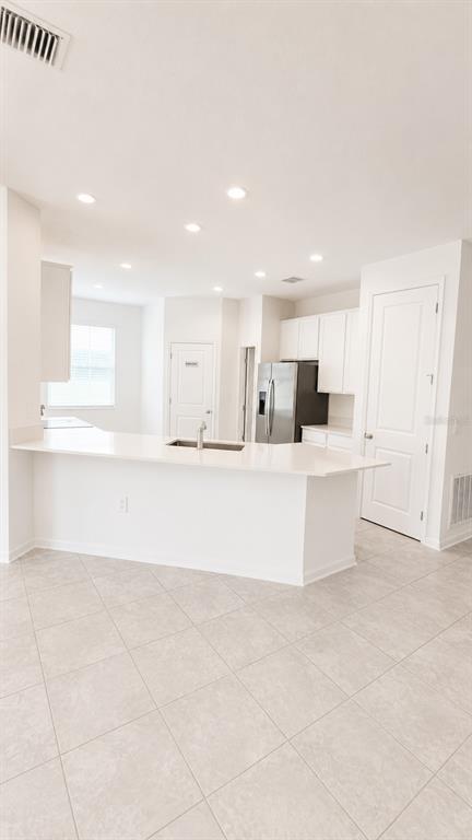 A kitchen features white cabinets, a breakfast bar with a sink, and light tile flooring — 506 HATTERAS ROAD, DAVENPORT, FL