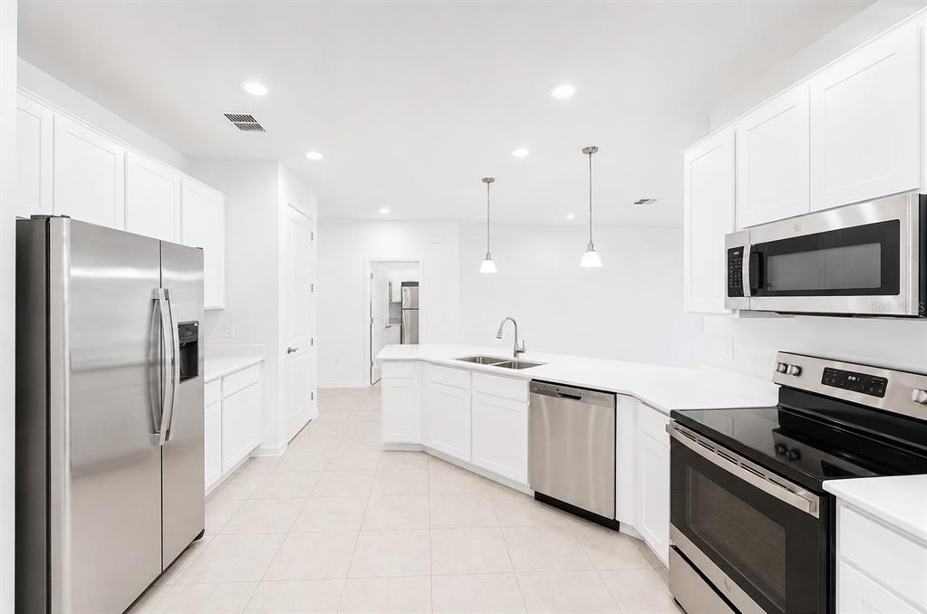 A modern kitchen features white cabinets, stainless steel appliances, and a central island with sink — 506 HATTERAS ROAD, DAVENPORT, FL
