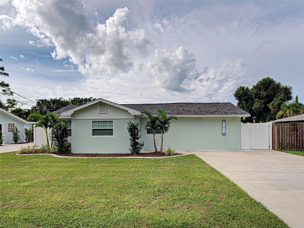 A light green single-story house features a concrete driveway, a front lawn, and palm trees — 425 YALE STREET, ENGLEWOOD, FL
