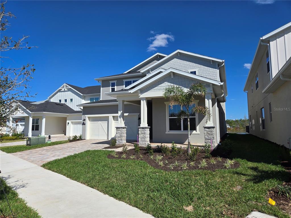 A two-story suburban house with a gray exterior, stone-accented columns, and a paved driveway — 13217 TOLLCROSS WAY, WINTER GARDEN, FL