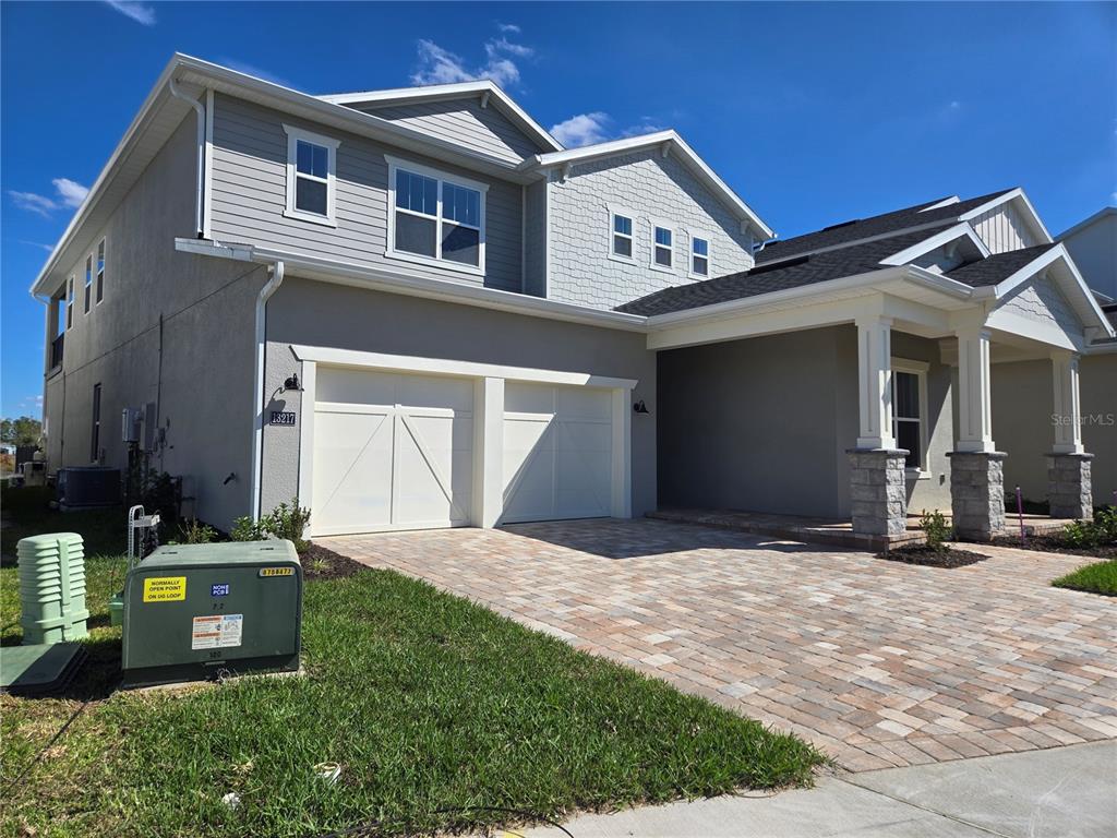 A two-story house with a two-car garage, stone-accented porch, and a paver driveway — 13217 TOLLCROSS WAY, WINTER GARDEN, FL