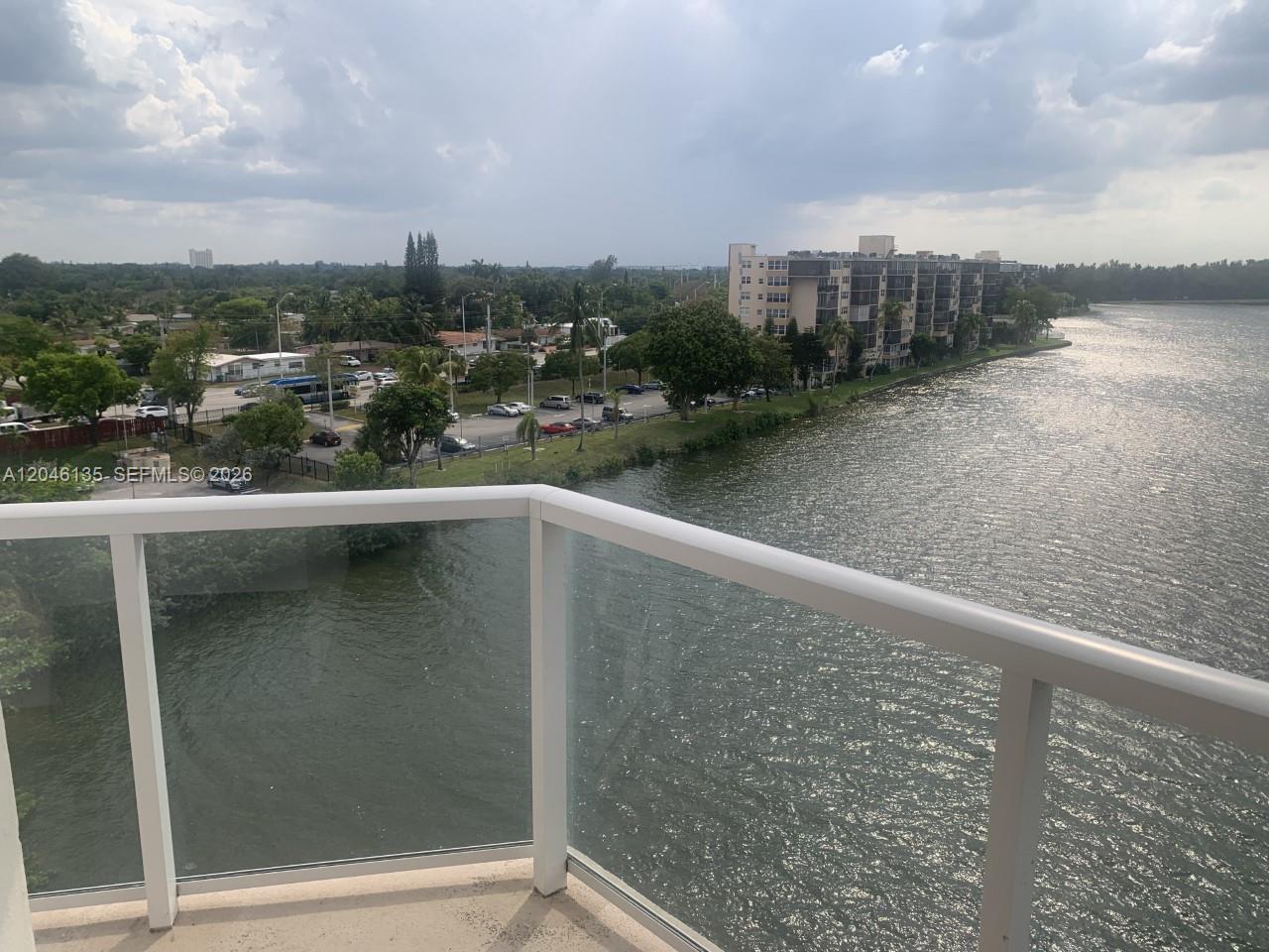 A balcony with a glass railing overlooks a lake and a residential neighborhood — MIAMI, FL
