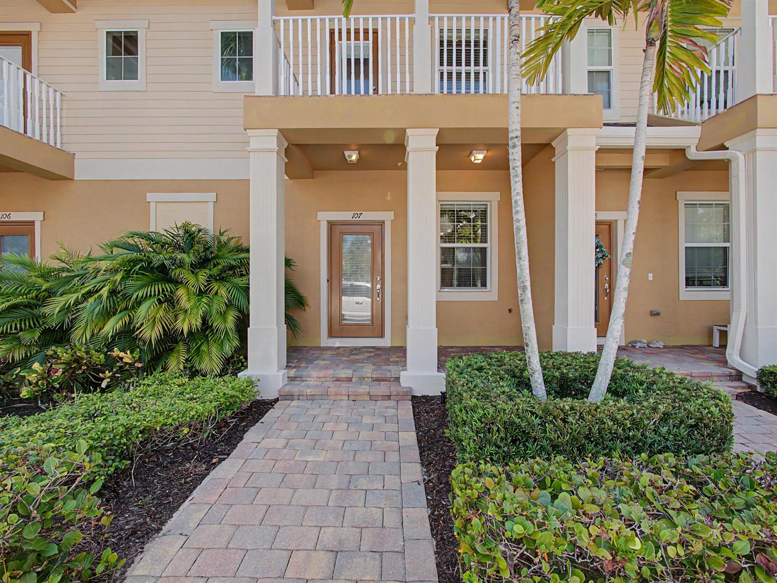 A paved walkway leads to the front entrance of a tan building with white columns — 118 Black Ironwood Road # 107, Jupiter FL 33458, JUPITER, FL