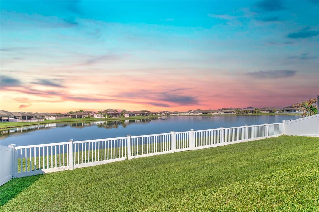 A white vinyl fence borders a grassy backyard overlooking a lake at sunset — 13821 TONYA ANNE DRIVE, RIVERVIEW, FL