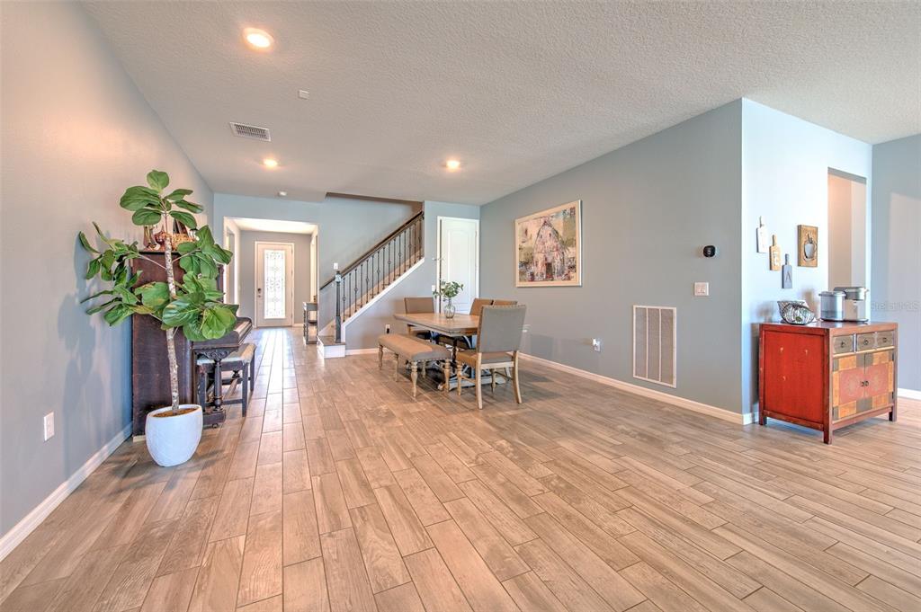 A dining area features wood-look tile flooring, a staircase, and a piano against the wall — 13821 TONYA ANNE DRIVE, RIVERVIEW, FL