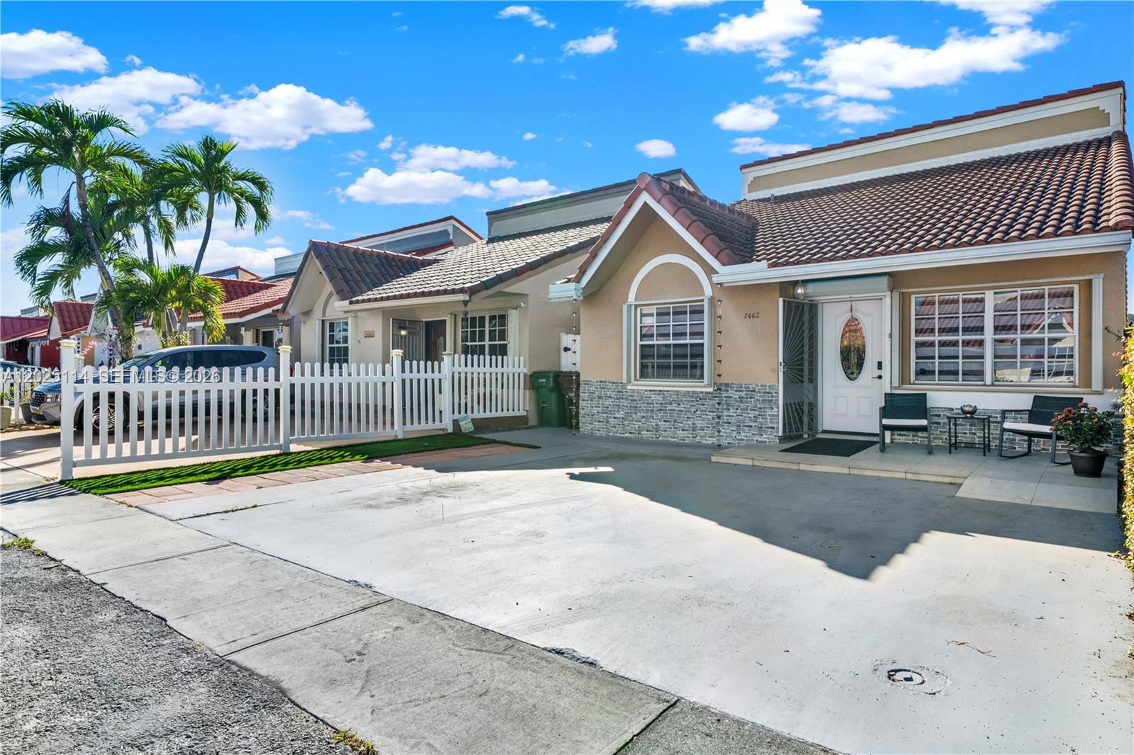 A single-story house with a concrete driveway, white picket fence, and a tiled roof — 7462 W 29th Way, Hialeah FL 33018, HIALEAH, FL