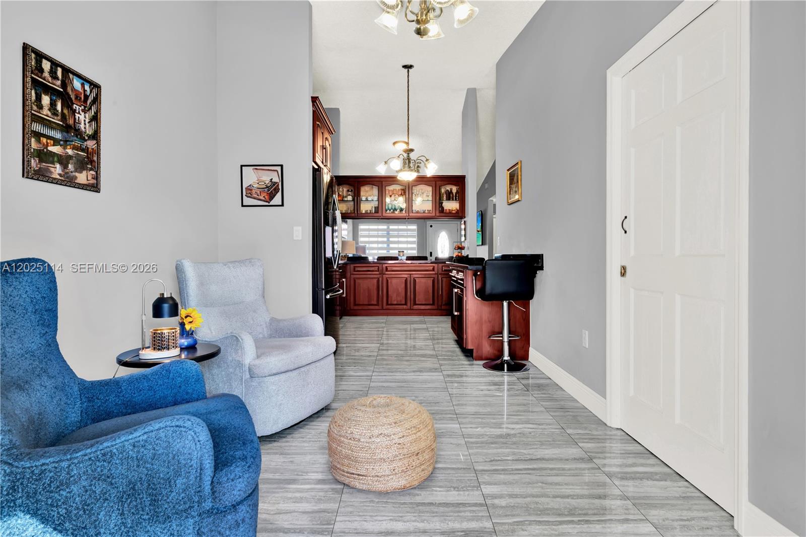 A living area with blue and gray armchairs leads to a kitchen with dark cabinetry — 7462 W 29th Way, Hialeah FL 33018, HIALEAH, FL