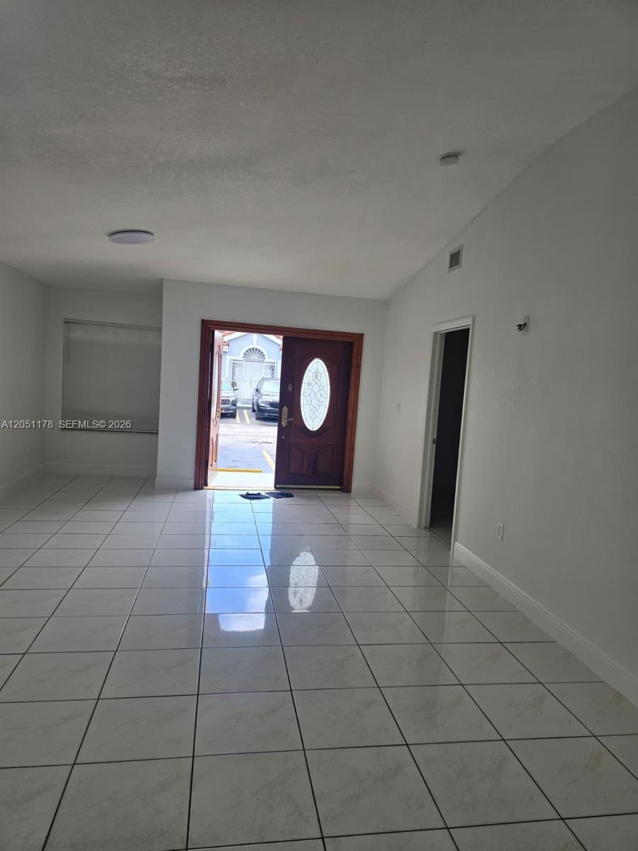 A room with white tiled floors and a wooden front door leading outside — 9069 NW 121st Ter # 81, Hialeah Gardens FL 33018, HIALEAH GARDENS, FL