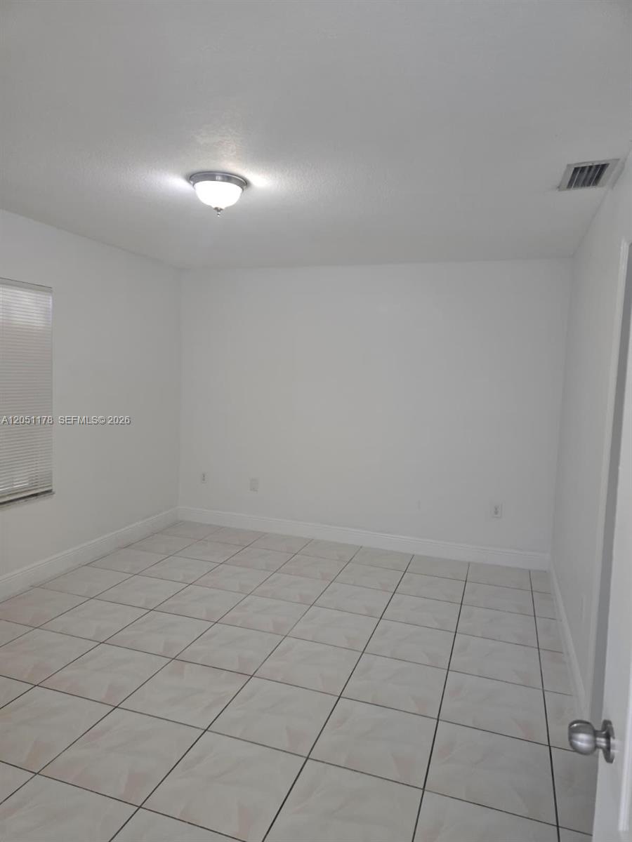 An empty room features white walls, a light-colored tiled floor, and a ceiling light fixture — 9069 NW 121st Ter # 81, Hialeah Gardens FL 33018, HIALEAH GARDENS, FL