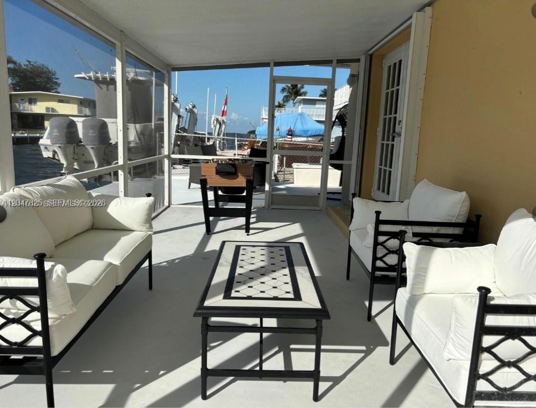 A screened-in patio features white cushioned furniture, a coffee table, and a view of boats — 235 Anne Bonny Dr, Key Largo FL 33034, KEY LARGO, FL