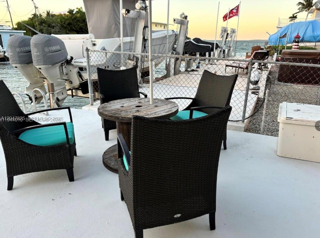 A patio area features a wooden spool table and four wicker chairs with turquoise cushions — 235 Anne Bonny Dr, Key Largo FL 33034, KEY LARGO, FL