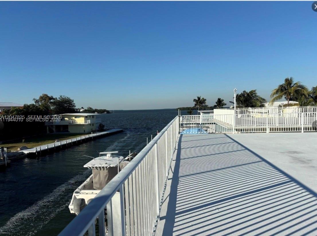 An elevated deck overlooks a canal with a boat and a wide expanse of water — 235 Anne Bonny Dr, Key Largo FL 33034, KEY LARGO, FL