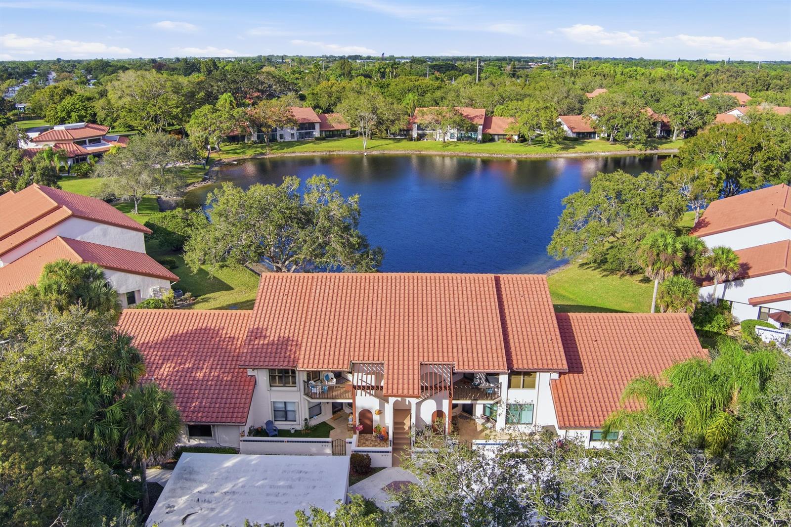 An aerial view shows a multi-story residential building with a red tile roof near a lake — 6100 SE Martinique Drive # 201, Stuart FL 34997, STUART, FL