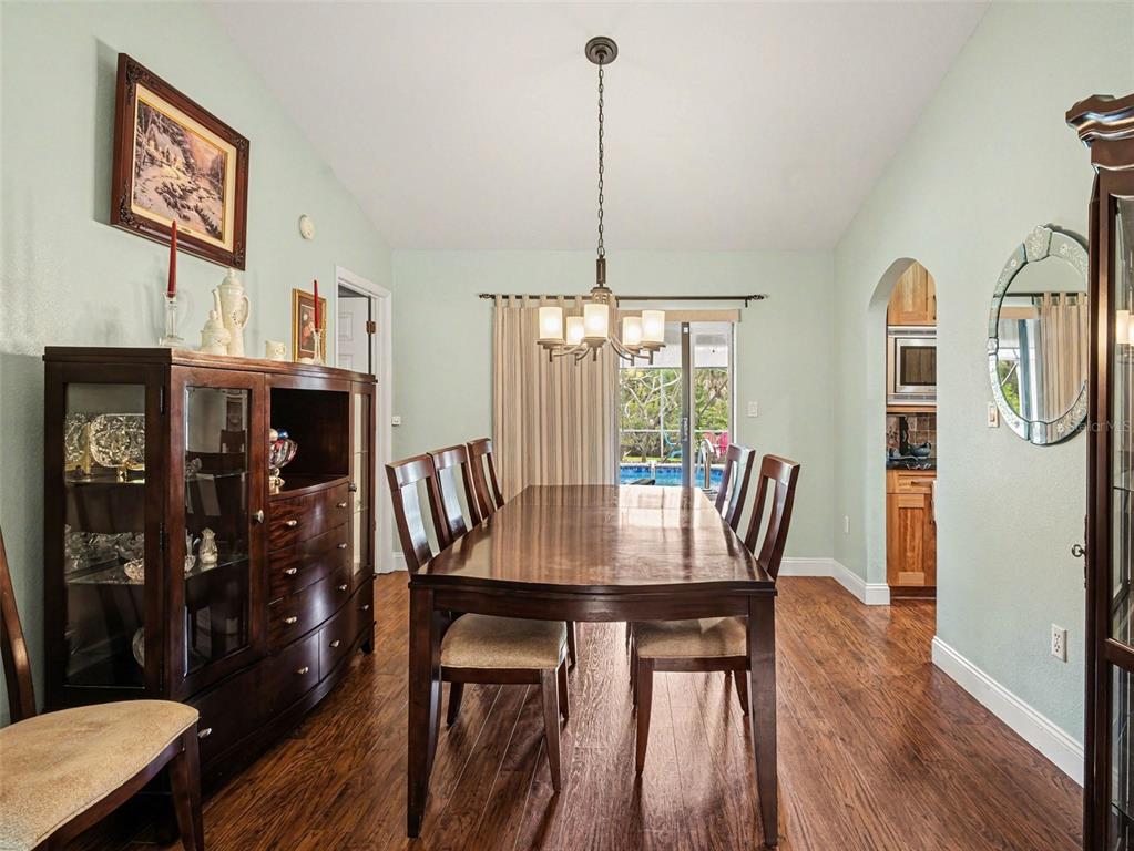 A dining room features a wooden table, chairs, a hutch, and a view of a pool — 507 RAMBLEWOOD STREET, PORT CHARLOTTE, FL