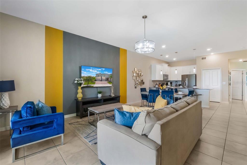 A living room with a gray and yellow accent wall, blue chair, and beige sofa — 1153 DROP LANE, DAVENPORT, FL
