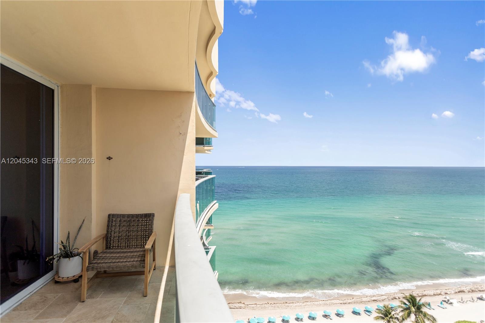 A balcony with a wicker chair overlooks the ocean and a sandy beach — 2501 S Ocean Dr # 1614, Hollywood FL 33019, HOLLYWOOD, FL