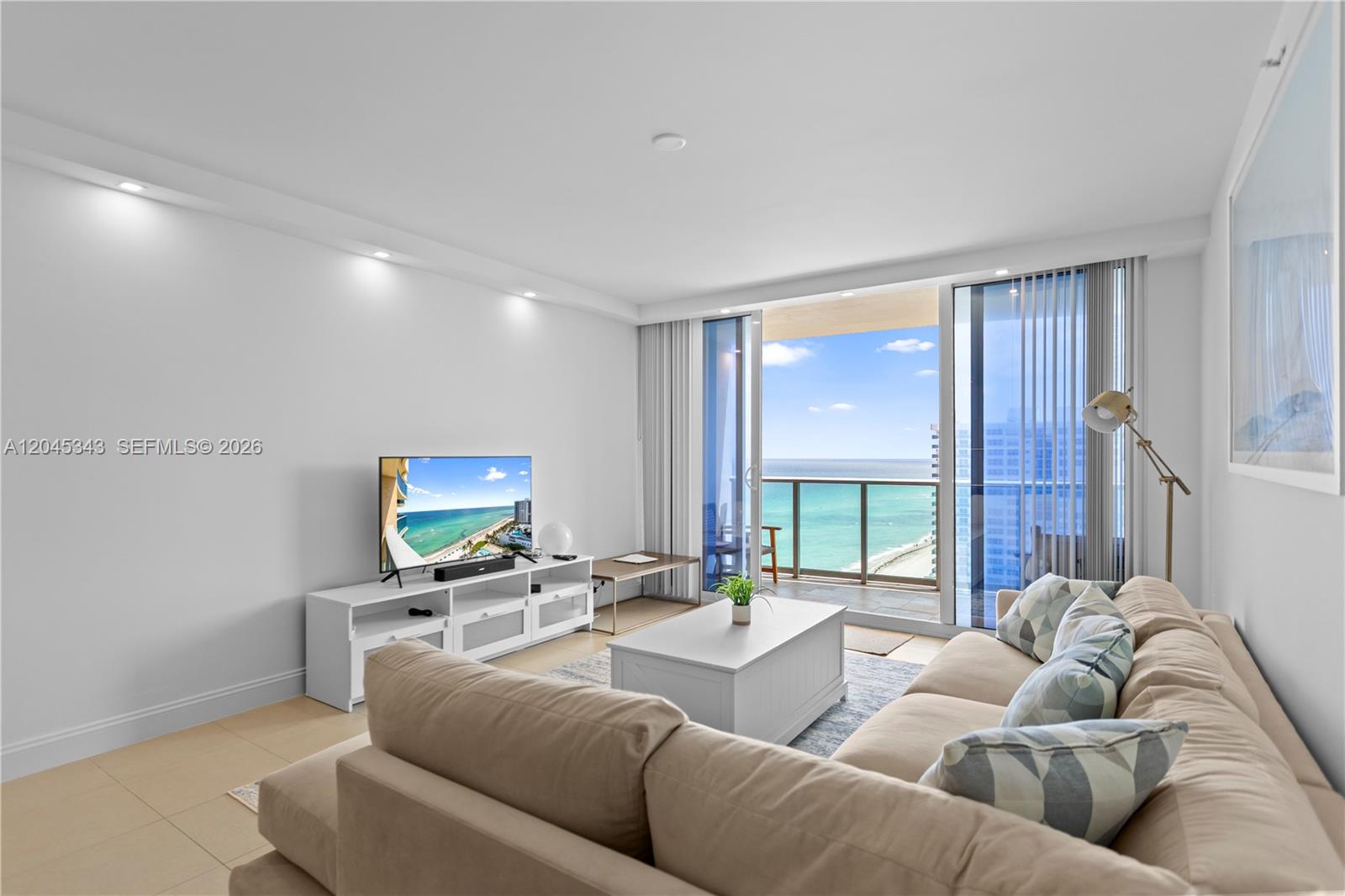 A living room features a beige sectional sofa, a white media console, and a balcony view — 2501 S Ocean Dr # 1614, Hollywood FL 33019, HOLLYWOOD, FL