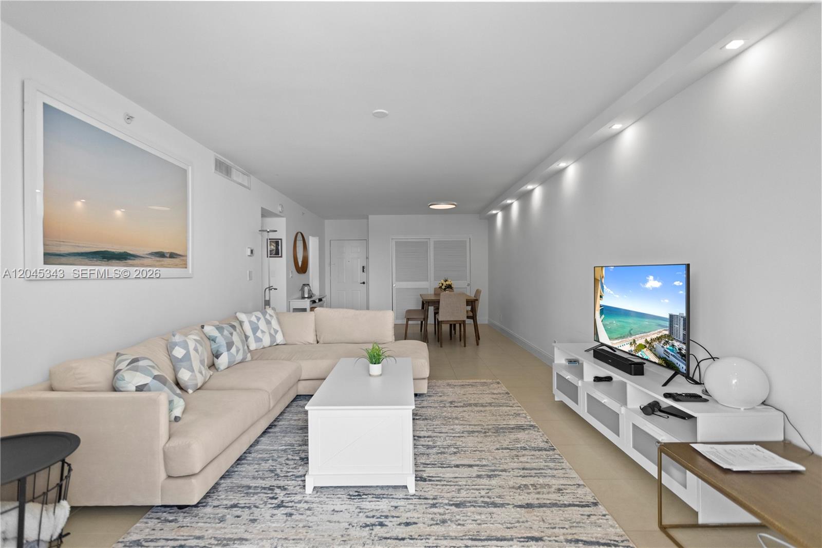 A bright living room features a beige sectional sofa, a white coffee table, and a television — 2501 S Ocean Dr # 1614, Hollywood FL 33019, HOLLYWOOD, FL
