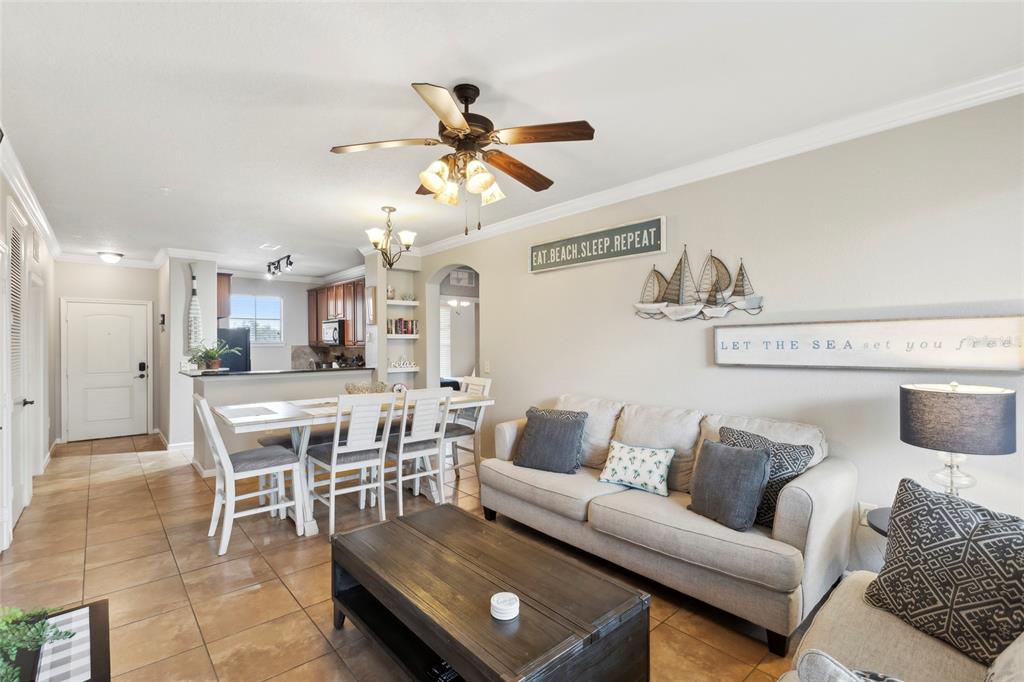 A living room and dining area with tile floors, a ceiling fan, and coastal wall decor — 901 CHARO PARKWAY UNIT 732, DAVENPORT, FL