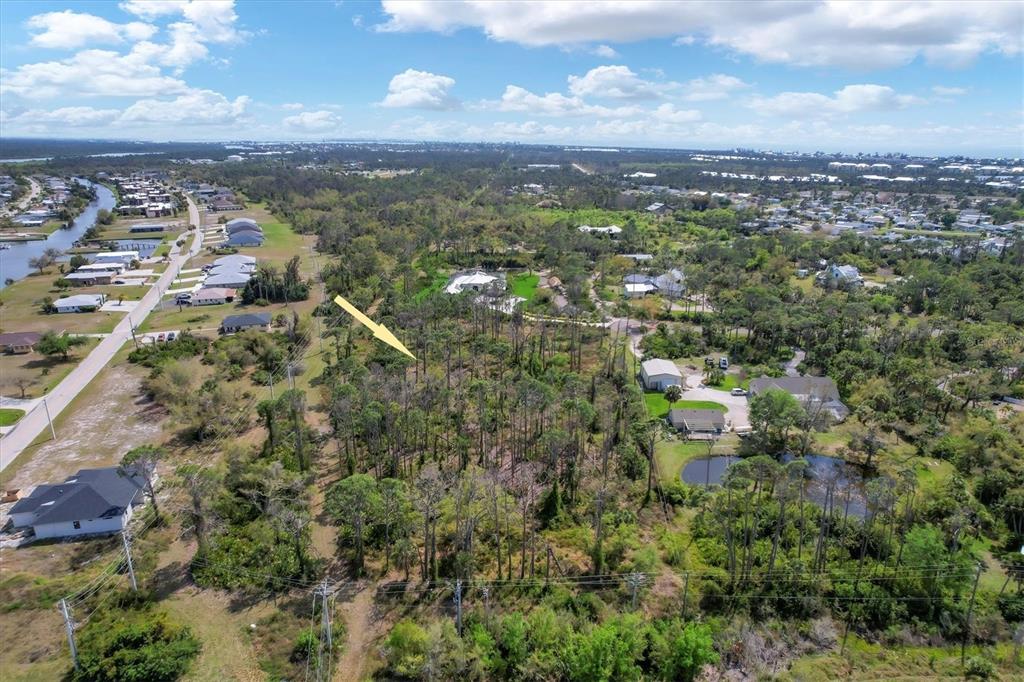 An aerial view shows a wooded residential lot marked by a yellow arrow — 9232 SPRING VALLEY ROAD, ENGLEWOOD, FL