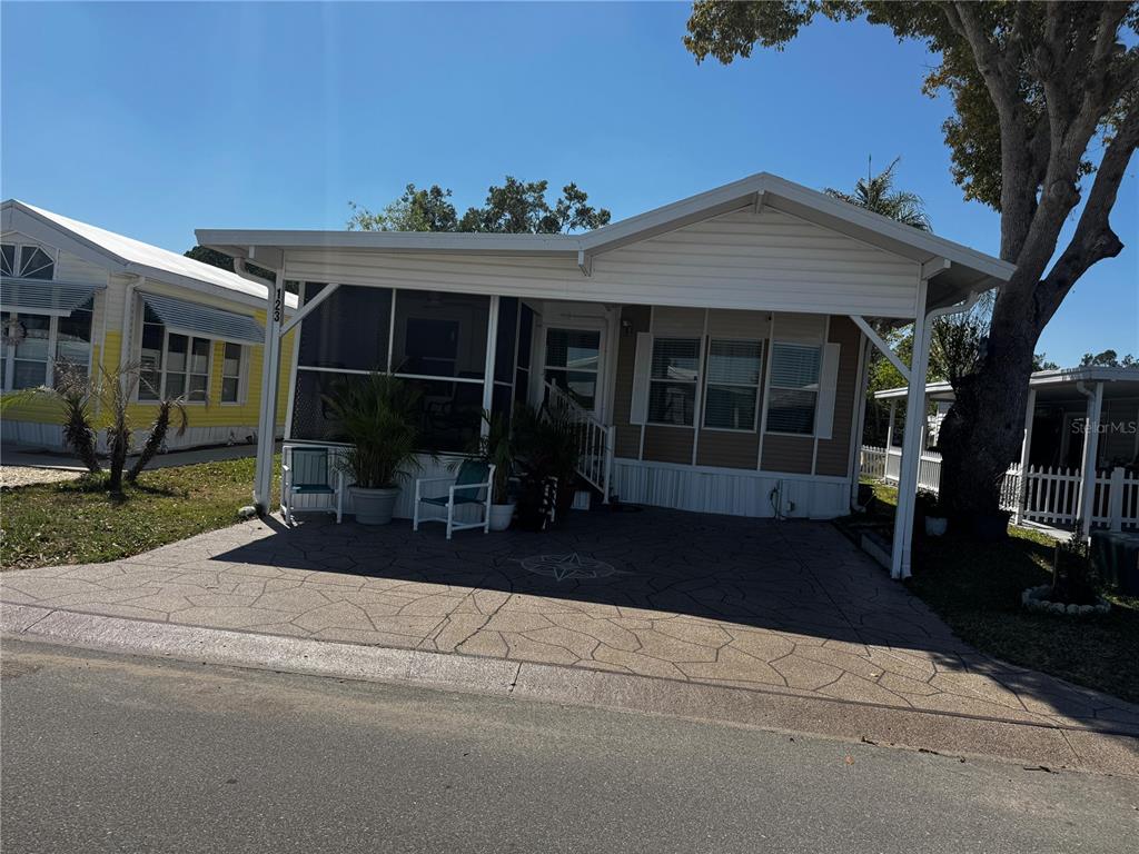 A tan mobile home with a screened porch and a patterned concrete driveway — 123 PANSY STREET, DAVENPORT, FL
