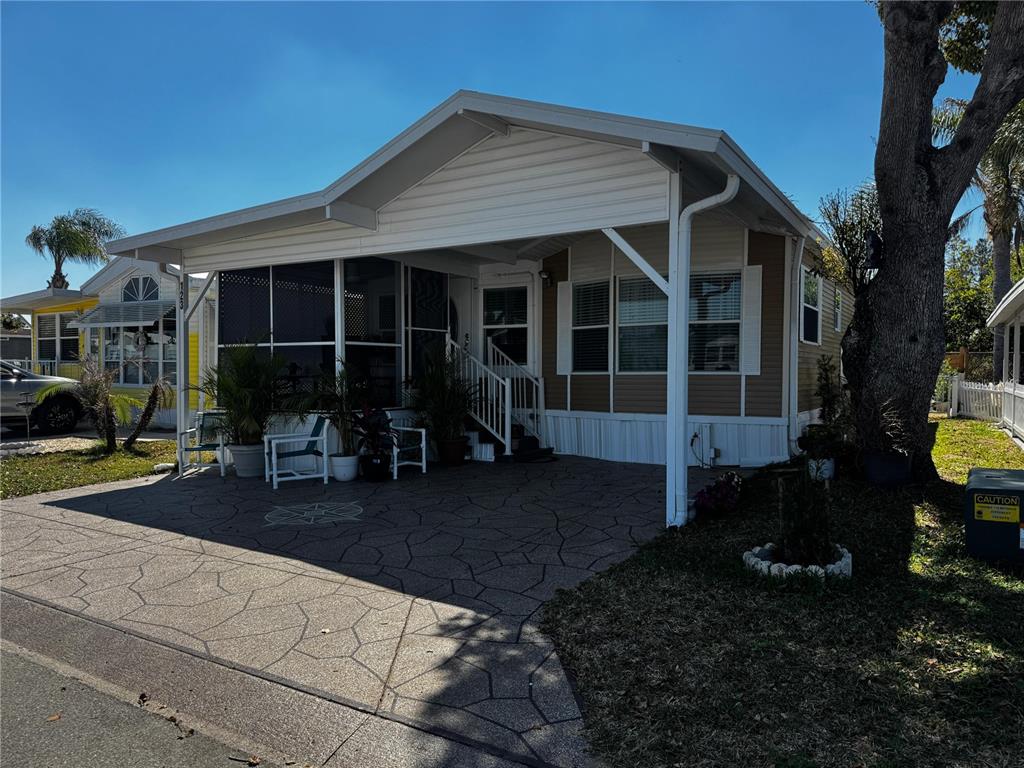A single-story manufactured home with a screened porch, carport, and patterned concrete driveway — 123 PANSY STREET, DAVENPORT, FL